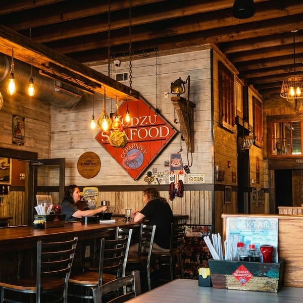 Two people seated at a rustic wooden bar in a restaurant with warm lighting and wood paneling.